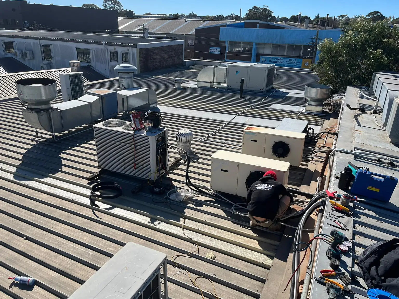 Refrigeration units and a technician working on a commercial rooftop during a production kitchen relocation